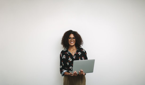 Portrait of a smiling businesswoman in office holding a laptop