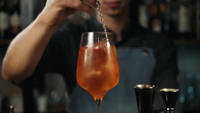 The barman pours Aperol into the cocktail of Aperol Spritz close up, bartender make alcohol drink