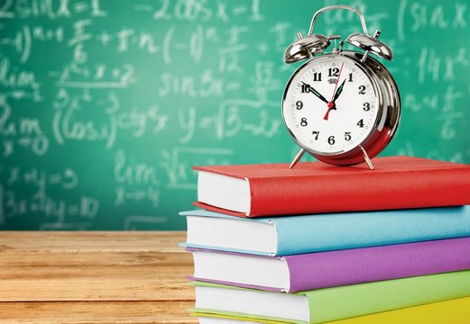 Pile of colorful books and alarm clock on top on white - Powered by Adobe