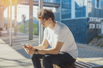 Close up of young man looking at mobile phone screen at metro station.