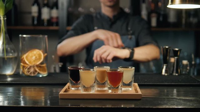 Beautiful row line of different colored alcohol cocktails bartender on a party, martini, vodka, and others on decorated catering bouquet table on open air event