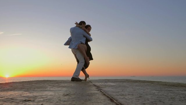 Energetic spanish couple against the background of the sunrise and ocean demonstrates elements of sensual Latin dance: bachata, rumba or kizomba. Slow motion