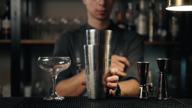 handsome smiling bartender with classical metal shaker in bar slow motion
