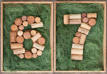 Number 67  sixty seven made of wine corks on green background in wooden box