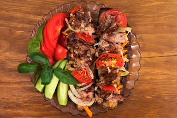 A portion of baked eggplant, which laid layers of roasted meat with tomatoes, onions and carrots, decorated with basil and slices of fresh cucumbers and tomatoes.