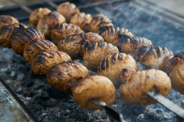 Baby potatoes grilled on skewers with lamb fat meat over coals