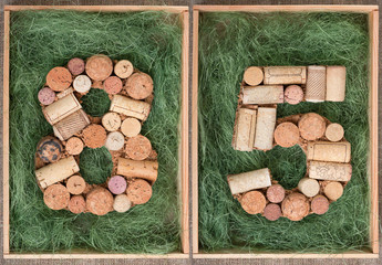 Number 85  eighty five made of wine corks on green background in wooden box