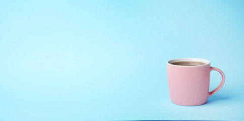Pink ceramic cup with hot aromatic coffee on color background