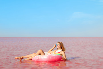 Naklejka premium Beautiful woman on inflatable ring in pink lake