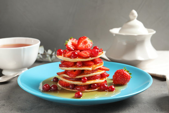 Tasty pancakes with berries and honey on plate