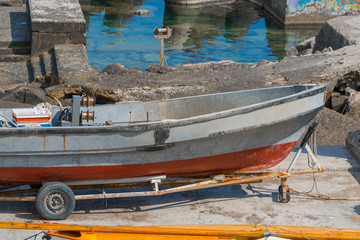 Obraz premium Old small fishing boat on trailer on shore under repair