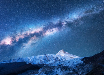 Milky Way above snowy mountains. Space. Fantastic view with snow covered rocks and starry sky at...