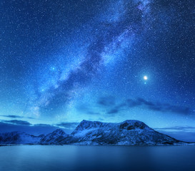Bright Milky Way over snow covered mountains and sea at night in winter in Norway. Landscape with...