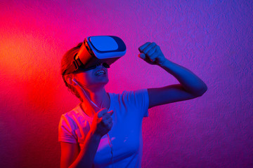 A cheerful girl with her hands up in virtual reality glasses.