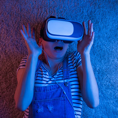 A cheerful girl with her hands up in virtual reality glasses.