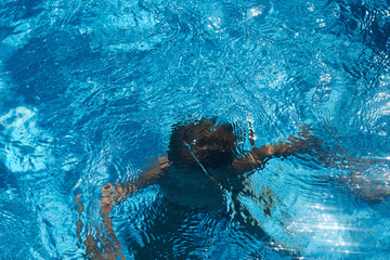 Drowning kid into swimming pool water. Young boy sinking into the sea.