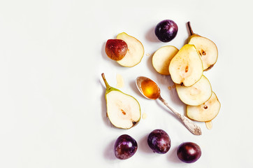 chopped pears. plum and a spoon of honey on a white background. view from above