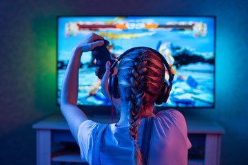 A gamer or a streamer girl at home in a dark room with a gamepad playing with friends on the...