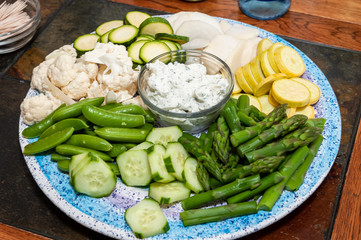 Crudite appetizer of raw vegetables and dipping sauce on a wooden table.
