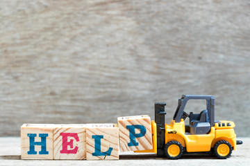 Toy forklift hold letter block P to complete word help on wood background