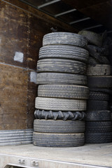 Old semi truck tires are piled in pile in semi trailer