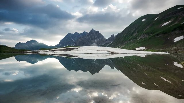 Time lapse symetrical reflection of clouds and sunrays in lake Eissee in Allgau Alps near Oberstdorf Bavaria Germany travel hiking mountains