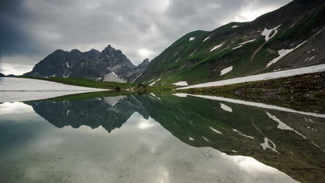 Time lapse symetrical reflection of clouds and sunrays in lake Eissee in Allgau Alps near Oberstdorf Bavaria Germany travel hiking mountains