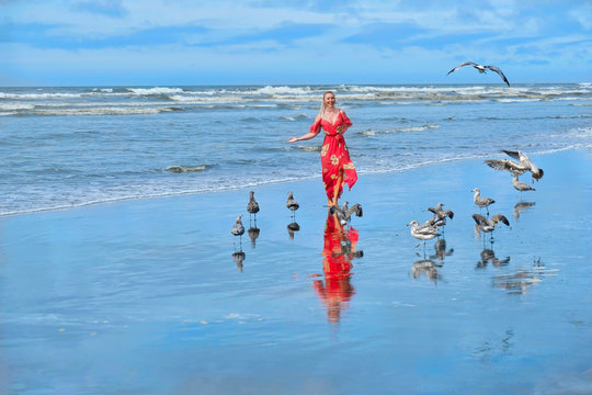 Beach vacation. Woman running on beach by sea with seagulls. Ocean Shores in Olympic Penincusula.  Seattle. Washington. United States of America.