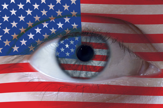 Human face painted with flag of USA on the face and the iris. The concept of the American view of life.