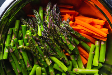 Bowl of carrots and asparagus cut and prepared for a stir fry.