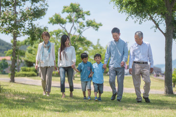 手を繋いで公園を歩く三世代家族