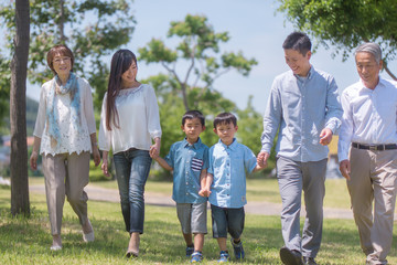 手を繋いで公園を歩く三世代家族