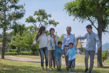 Obraz premium 手を繋いで公園を歩く三世代家族