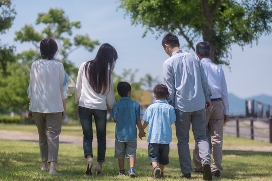 手を繋いで公園を歩く三世代家族の後ろ姿