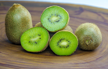 Sliced fresh and juicy kiwi fruit halves on a wooden background.
