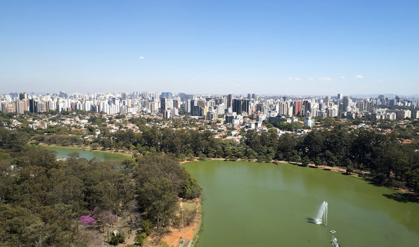 Aerial view of Ibirapuera park in Sao Paulo city, Brazil. Prevervetion area with trees and green area of Ibirapuera park. Office buildings and apartments in the background on a sunny day.
