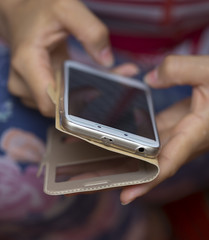 A girl is holding a phone and writing an SMS