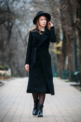 Outdoor portrait of a romantic, pretty elegant business of a long-haired woman, enjoying a stroll through the city. Photo of a adorable girl in a hat with curly hair