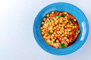 Fototapeta na wymiar Overhead image dish Chickpea hummus and tahini dipped with olive oil, pepper, parsley, spices on a white table background. Hummus Traditional Middle Eastern food commonly served in a pita. Copy space.