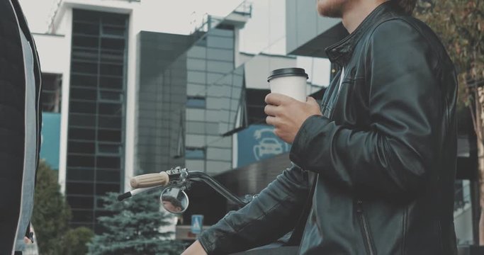 Two friends motorcyclists men meet on the street and shake hands with each other. Guys bikers in the leather jackets talking. Urban lifestyle scene. 4K video shooting by handheld gimbal