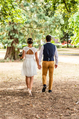 Bride and groom holding hand and walk in the garden
