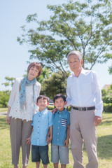 Fototapeta premium 公園で微笑むシニア夫婦と孫