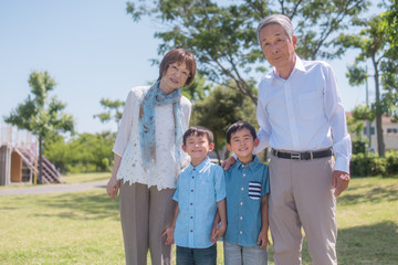 公園で微笑むシニア夫婦と孫