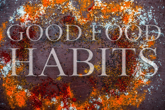 Spices powder on brown colored wooden surface including salt and pepper with written Good Food Habits on it. - Powered by Adobe