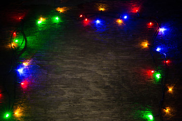 multicolored Christmas lights on a wooden background