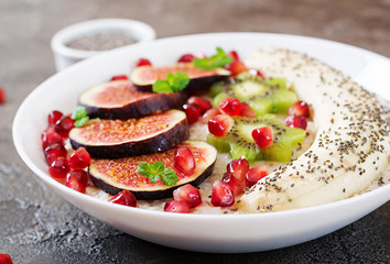 Delicious and healthy oatmeal with figs, kiwi, pomegranate, banana and chia seeds. Healthy breakfast. Fitness food. Proper nutrition.