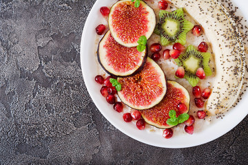 Delicious and healthy oatmeal with figs, kiwi, pomegranate, banana and chia seeds. Healthy breakfast. Fitness food. Proper nutrition. Flat lay. Top view.