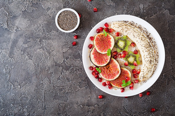 Delicious and healthy oatmeal with figs, kiwi, pomegranate, banana and chia seeds. Healthy breakfast. Fitness food. Proper nutrition. Flat lay. Top view.