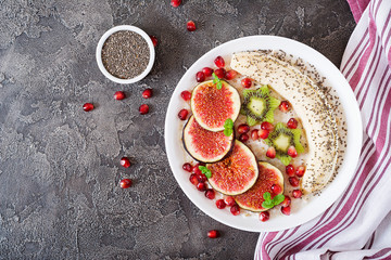 Delicious and healthy oatmeal with figs, kiwi, pomegranate, banana and chia seeds. Healthy breakfast. Fitness food. Proper nutrition. Flat lay. Top view.