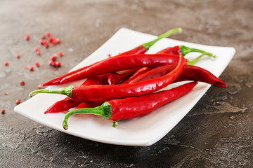 Red hot chili peppers  in plate on grey table. Top view
